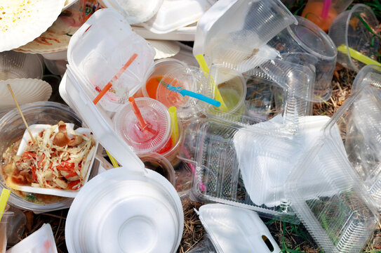 Pile of used plastic containers, cups, plastic waste, takeaway food packaging outdoors, highlighting single-use waste, environmental pollution, consumer habits, and recycling challenges