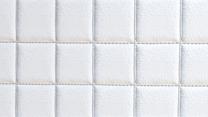 Naklejka premium The surface texture of white faux leather, stitched in diamond, square, and rectangular patterns. Quilted eco-leather