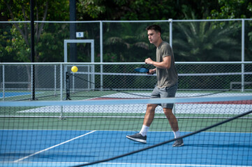 Obraz premium Young male athletes playing pickleball and practicing for competition on an outdoor field