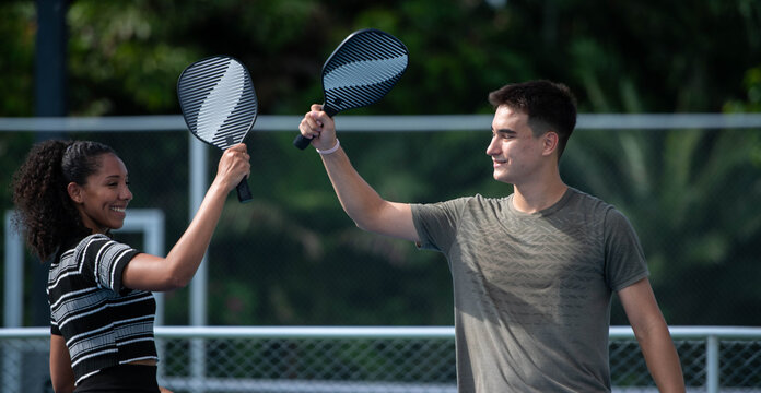Mixed doubles pickleball teammates celebrating a successful play by tapping paddles