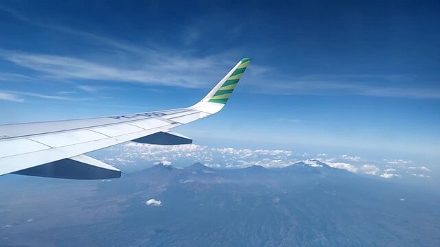 Dreamy aerial view of soft clouds and ocean islands at daytime from plane window.