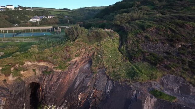 Fast zoom out from pathway to sea at Crackington Haven Cornwall evening time