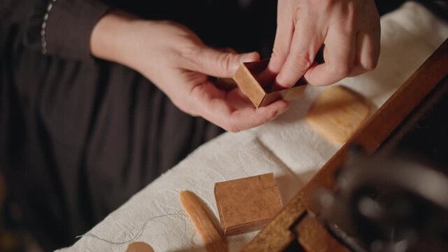 Closeup hands assembling tiny compartment, tailor fitting dividers and bobbins into compact case, precise joinery and gentle fingertips, warm lamplit studio vibe, concentrated artisan work