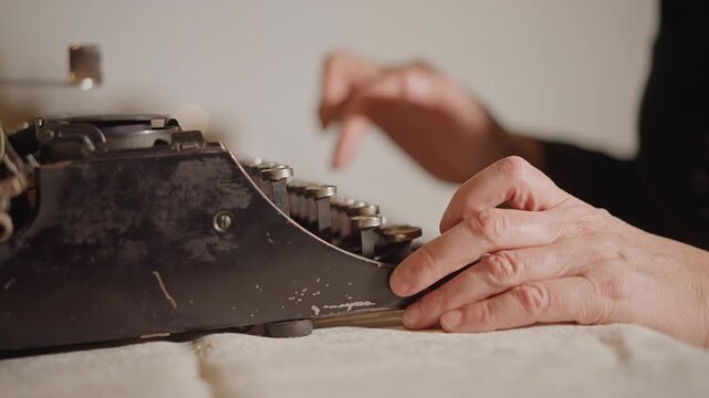 Closeup aged hands typing on typewriter, textured skin and steady fingers strike keys, slow cinematic motion with soft shadows, tactile sound of metal type and intimate portrait of experience.