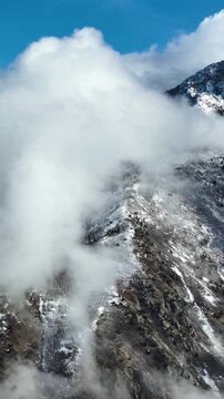 Aerial shot of the clouds and the rugged terrain of the Wasatch Mountains near Salt Lake City, Utah. Vertical Video.