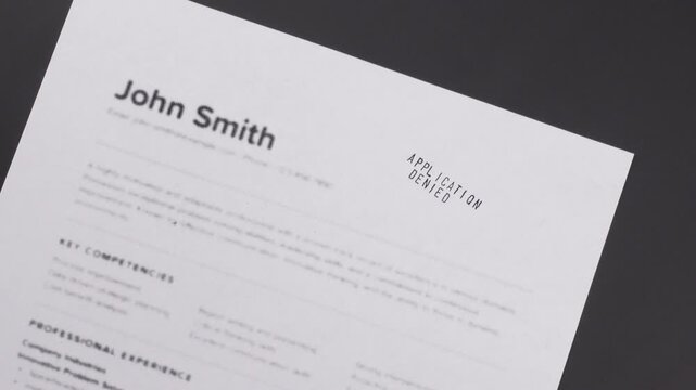Fake mock CV (curriculum vitae) rejected by HR with Application Denied stamp. Concept of job search, recruitment process, rejection, downsizing, restructuring, and job loss.