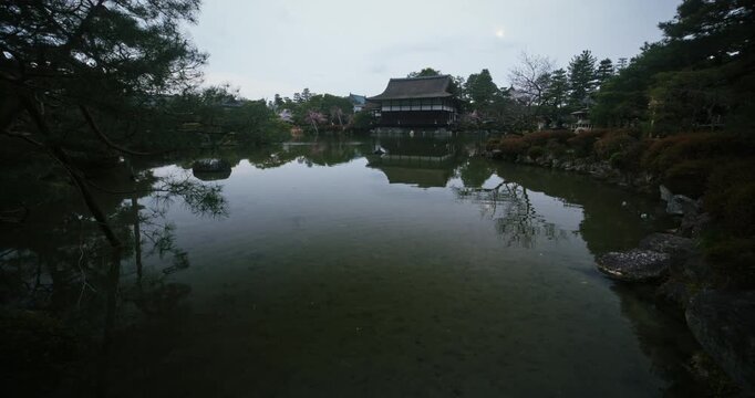 Beautiful reflection in pond of spring trees and old Japanese structure - wide shot