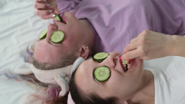 Two girlfriends are relaxing at home in the bedroom and making a face mask. Cheerful rest of two women in pajamas. Cosmetic procedures. Skin care.
