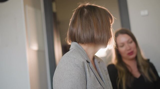Caucasian vocal coach giving feedback student near doorway light, two women exchanging expressive cues, warm backlight, rehearsal vibe, mentor providing critique and guidance during lesson