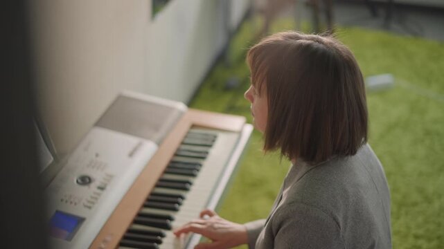 White musician singing and playing piano outdoors on green lawn, expressive profile with sheet music, natural daylight, intimate rehearsal blending voice and keys, reflective creative mood