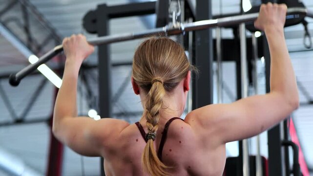Fit Woman Performing Lat Pulldown Exercise In Modern Gym