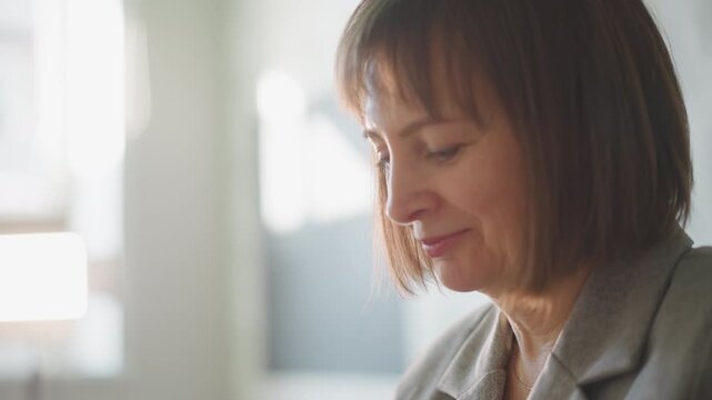 Woman teacher in sunlit classroom planning lesson and reviewing notes, soft natural light closeup profile showing concentration and gentle smile, sheet music and papers on desk, calm professional