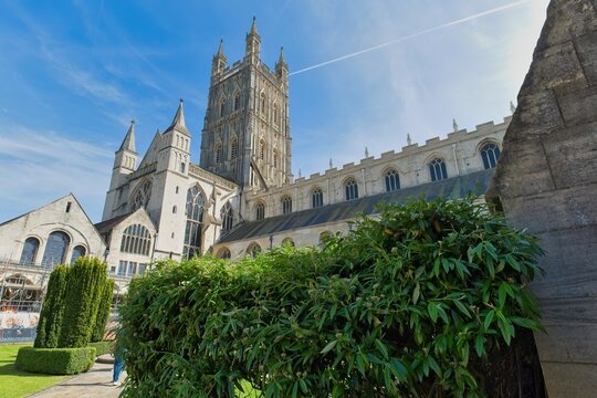 A magnificent stone cathedral with a tall central tower under a bright blue sky at Gloucester Cathedral - Gloucester - Gloucestershire - UK