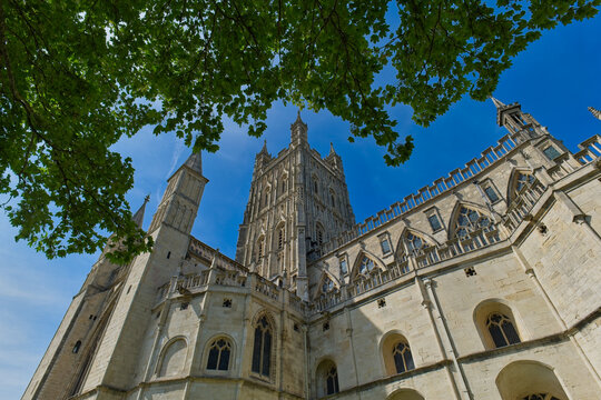 A striking low-angle shot of a grand stone cathedral with a central tower against a vibrant blue sky at Gloucester Cathedral - Gloucester - Gloucestershire - UK