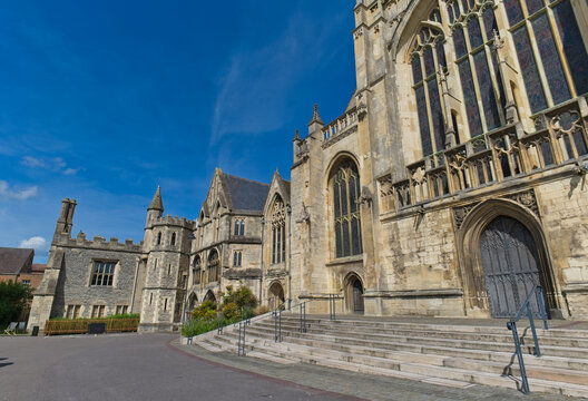 A majestic stone cathedral or university building stands under a bright blue sky at Gloucester Cathedral - Gloucester - Gloucestershire - UK