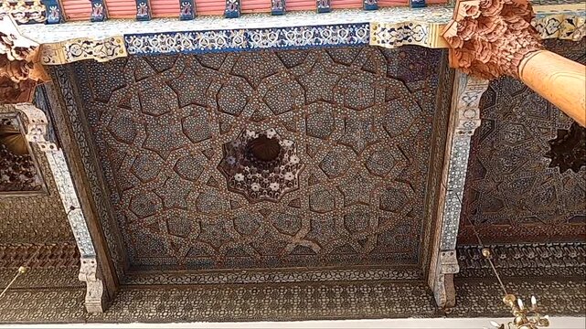 Close-up pan of intricately painted wooden ceiling at Bolo Hauz mosque