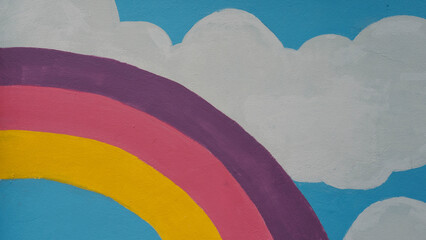 Bright colorful rainbow and clouds mural painted on concrete wall texture background. © RilakkuMaxx