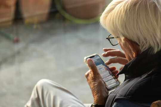 elderly man typing on smart phone outdoors at sunset
