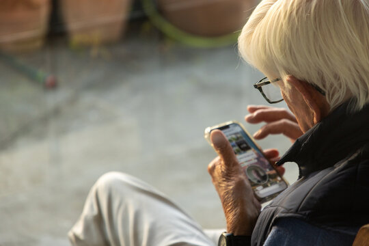 elderly man typing on smart phone outdoors at sunset