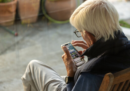 elderly man typing on smart phone outdoors at sunset