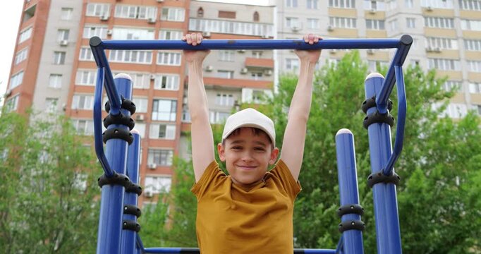 Young boy enjoys playground activity, hanging on monkey bars in urban park. Bright sunny day creates cheerful atmosphere. Fun and fitness encourage outdoor play.