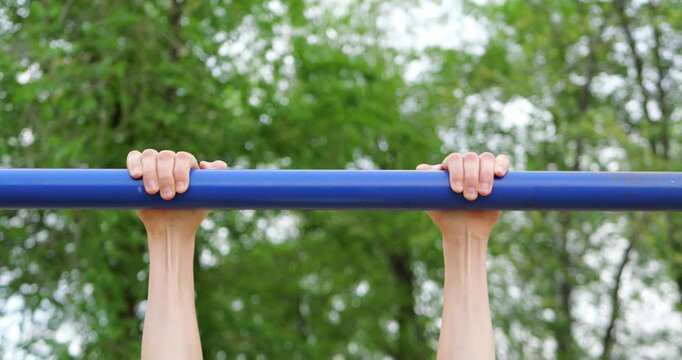Close-up of childs hands gripping pull-up bar during outdoor workout in sunny park. Active childhood scene captures strength development, determination and healthy lifestyle through exercise.