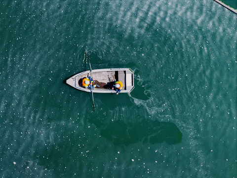 Two workers rowing small boat on green reservoir water control of Copper, iron ore mining industry sludge ponds, tailings storage facilities