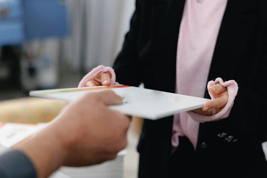 Hands exchanging documents in office setting for business transaction background and corporate communication