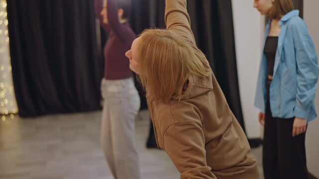 White male coach applauding in studio, hoodiewearing mentor clapping hands while students move in background, encouraging atmosphere, rehearsal climax with supportive feedback, warm lights,