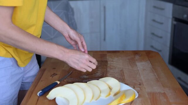 Person slicing fresh yellow melon on wooden cutting board in home kitchen Full HD preparation video