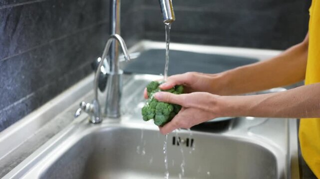 Washing fresh broccoli under running water in modern kitchen sink video Full HD