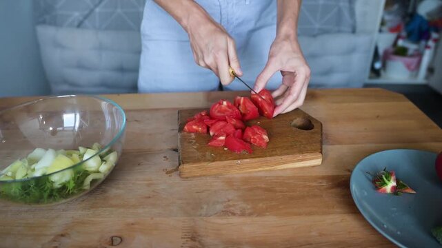 Woman cutting ripe red tomato into pieces for fresh homemade vegetable video Full HD salad