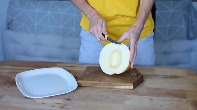Woman preparing yellow melon on cutting board in home kitchen Full HD video