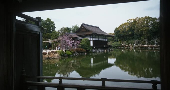 Light rain over reflective pond near Japanese structure - wide shot