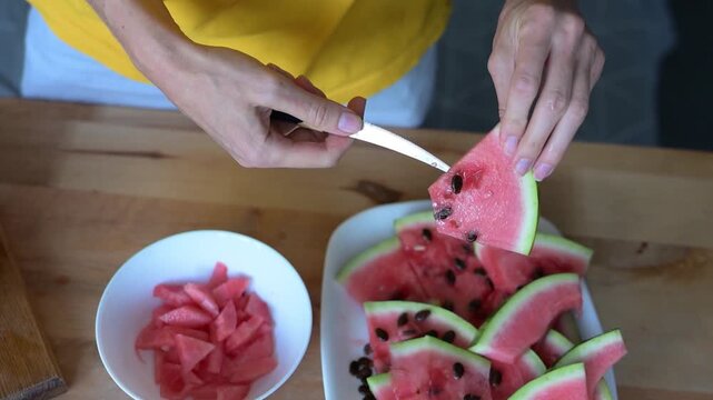 Woman removing knife after cutting watermelon into equal slices at HD video home Full