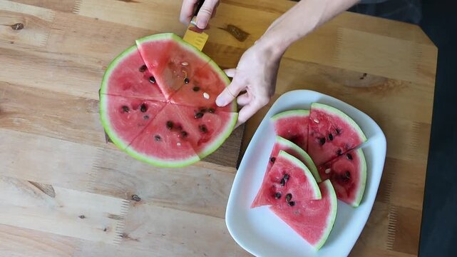 Woman cutting fresh watermelon into slices on wooden table in home Full HD video kitchen