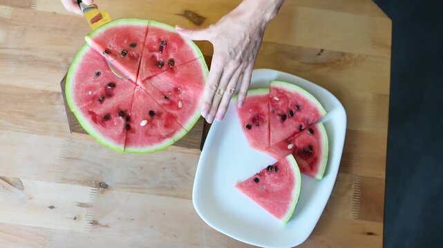 Woman cutting fresh watermelon into slices on wooden table in home kitchen Full HD video