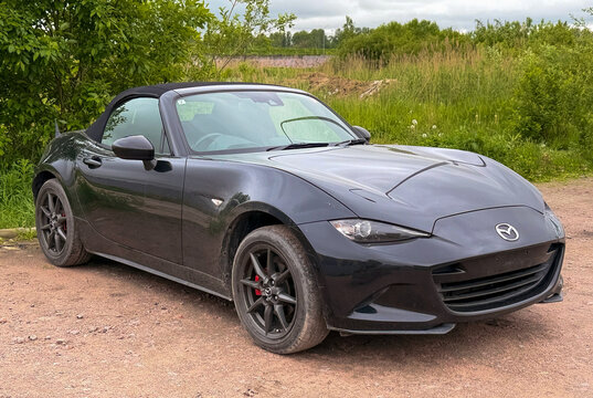 A stylish Mazda MX-5 RF Miata Sport Tech, two door sports car convertible black color, in a carpark at the city. Exterior of a Mazda MX-5 Miata RF Roadster fastback model. JDM.
