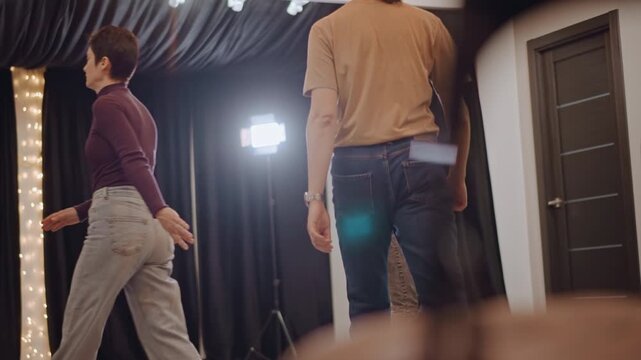 Actors walk steadily in front of curtain. Quiet rehearsals see actors practicing their scenes carefully. Performers move with calmness as actors rehearse their lines and actions quietly
