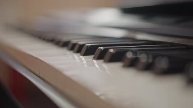 Close up piano keys during practice. Soft natural light and shallow depth of field highlight ivory and ebony texture, subtle fingertip motion and key wear evokes focused student rehearsal, teacher