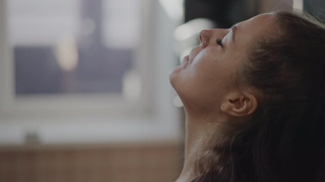 Performer practicing breathing techniques and gentle neck stretches in studio. Studio artist performing vocal exercises alongside relaxing gestures and sunlight for audition readiness