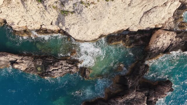 Top Down Drone View of Waves Crashing Against Rocky Cliffs on Lefkada Coast