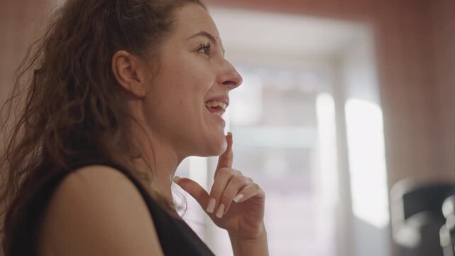 Young caucasian vocal coach singing warmup in sunlit studio, side profile closeup shows expressive mouth, thoughtful finger gesture and breath control exercises, intimate teaching atmosphere