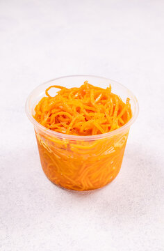 Korean carrot salad in plastic container on white background
