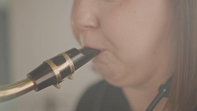 Closeup sax mouthpiece embouchure practice student concentrating during private lesson, instructor coaching offcamera, warm studio light, subtle reed vibration, breath control drills, focused