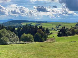 Obraz premium panorama of beautiful countryside of Rhoen, Hesse, Germany. sunny afternoon. wonderful springtime landscape in mountains. grassy field and rolling hills. rural scenery.