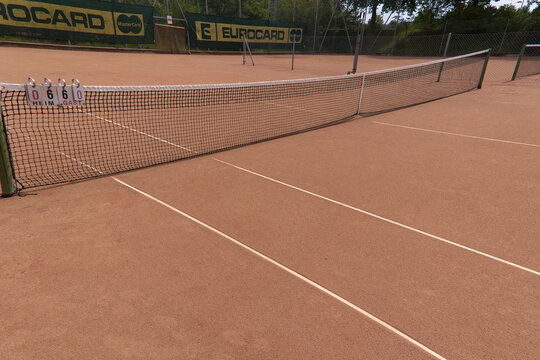 Red sandy tennis court with net and Mastercard advertising at Swiss city of Z&uuml;rich on a sunny spring day. Photo taken May 30th, 2026, Zurich Seebach, Switzerland.