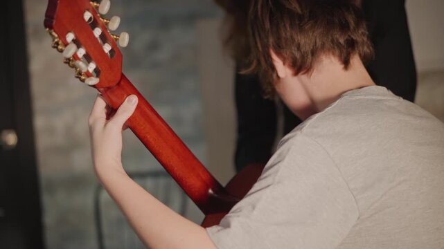Focused young musician carefully practicing guitar skills silently and effectively. Committed adolescent student is quietly rehearsing and sharpening their guitar playing abilities