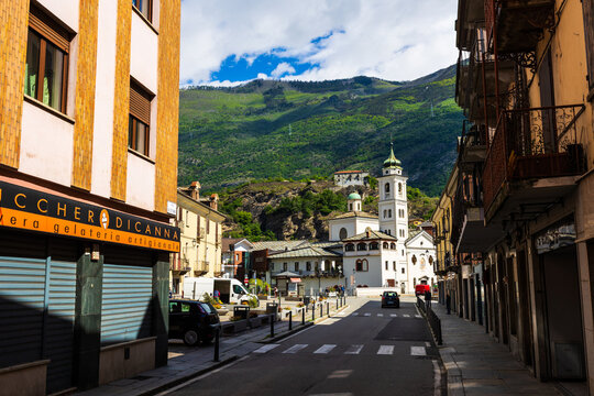 White facade of the Santa Maria del Ponte church seen through an alleyway in the city center of Susa
