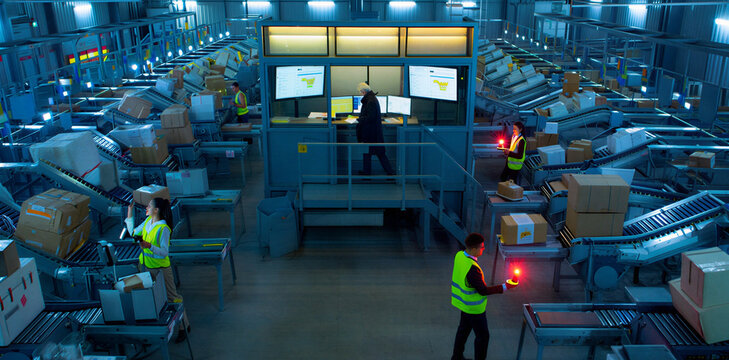 Operators managing automated packaging line in high tech warehouse with logistics warehouse automation packaging industrial manufacturing technology conveyor management facility